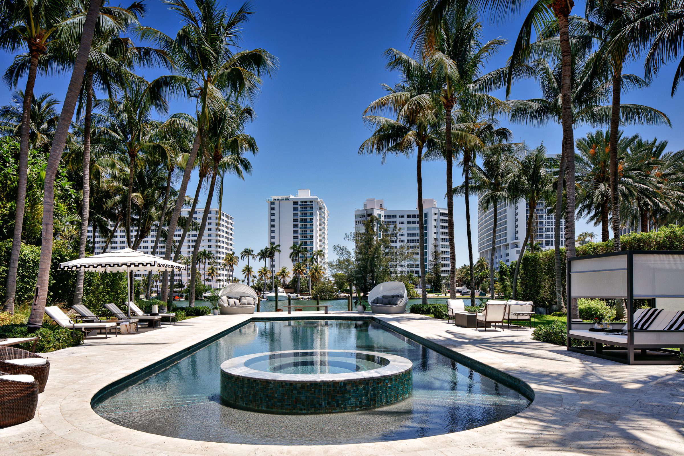 Waterfront terrace with an Olympic-sized pool, cabanas, and palms, planned as a series of outdoor rooms.