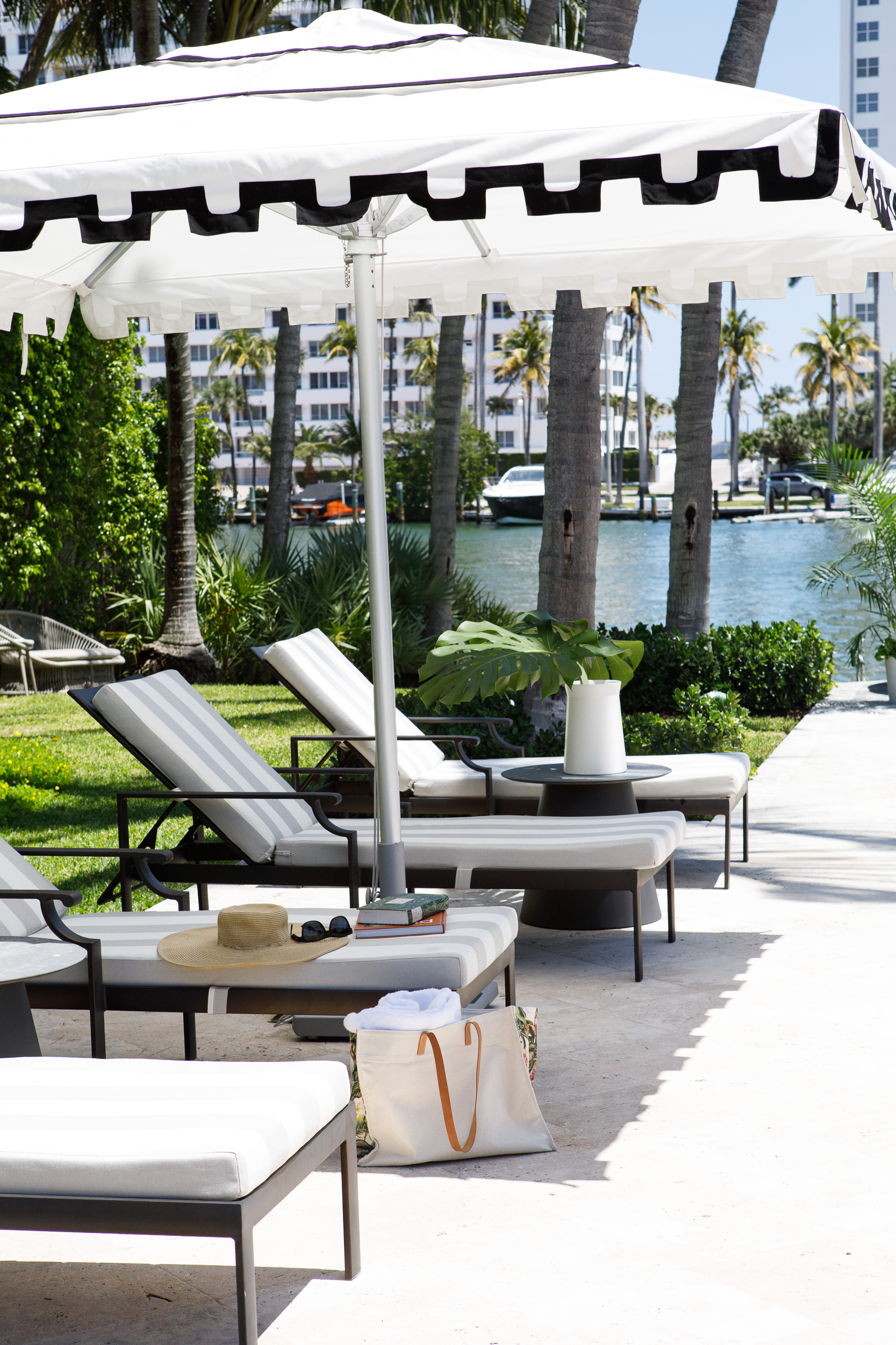 Striped loungers beneath a fringed black-and-white parasol overlooking the water.